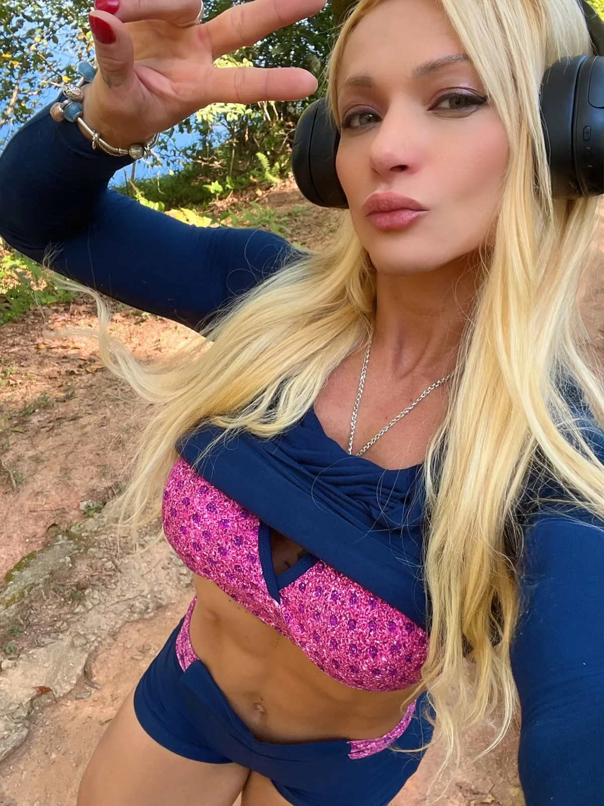 Selfie de Evelyn Soares ao ar livre, de fone de ouvido e blusa azul